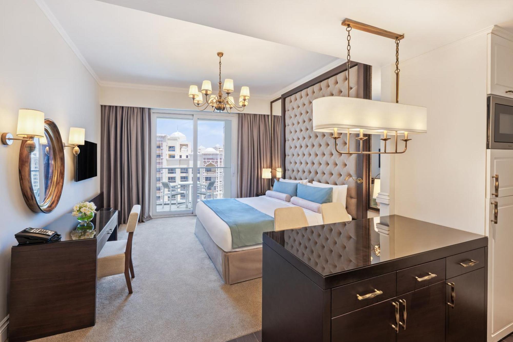 Dukes The Palm, A Royal Hideaway Hotel Dubaj Zewnętrze zdjęcie The photo shows a luxurious hotel room featuring modern decor. The room includes a large bed with a tufted headboard, soft bedding in light colors, and stylish furnishings. There is a desk and a chair in one corner, along with a decorative mirror and